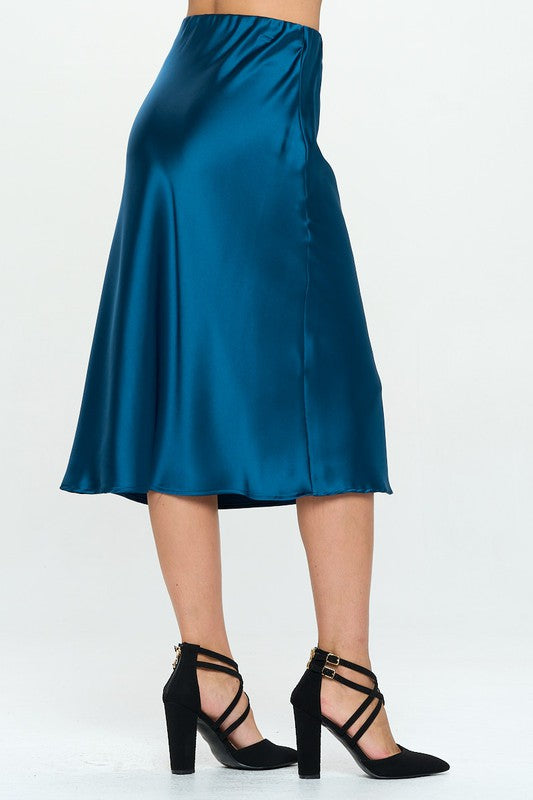 Jade Icarus Made in USA solid satin midi skirt, displayed in a fashion photoshoot setting, showcasing its smooth fabric and elegant length.