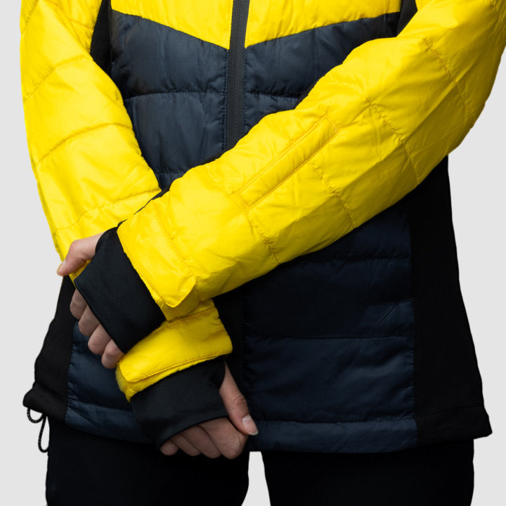 Women’s yellow EcoDown jacket by Rose Hemera, activewear with a lightweight, insulated design, shown on model in outdoor setting.
