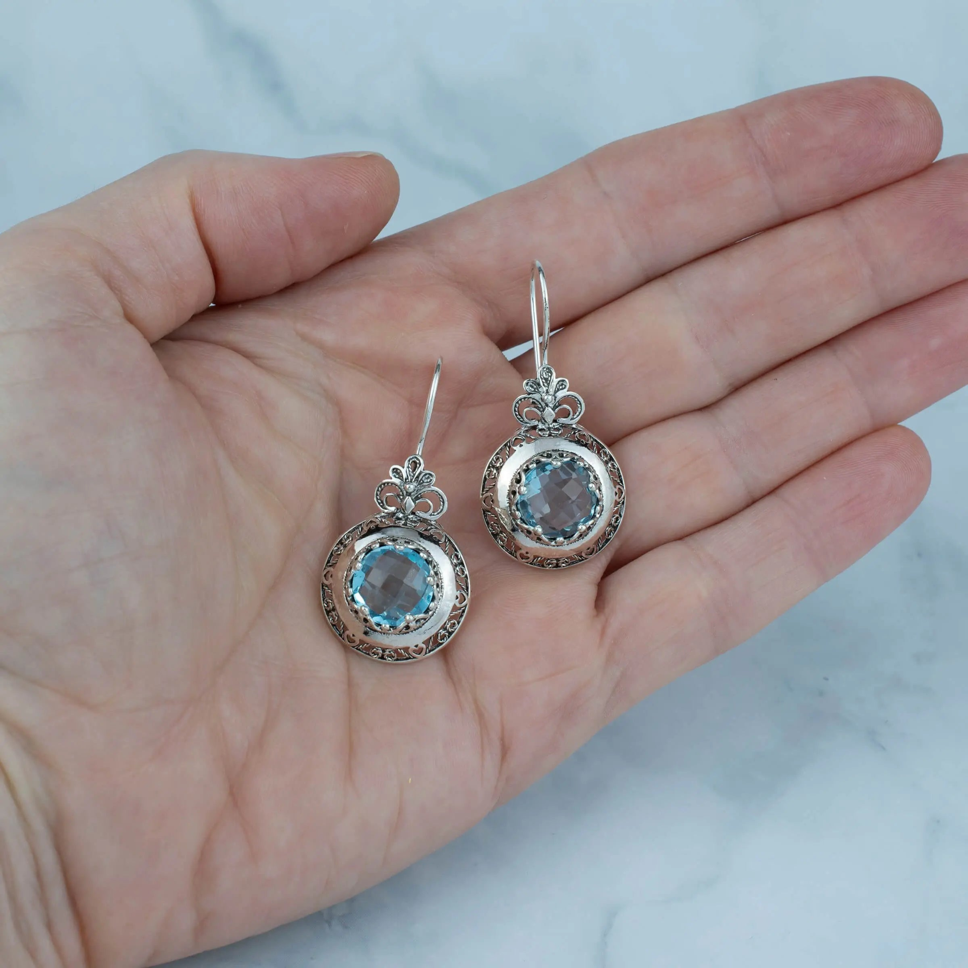 Silver drop earrings with filigree floral design and blue topaz gemstones for women, featuring intricate jewelry craftsmanship.