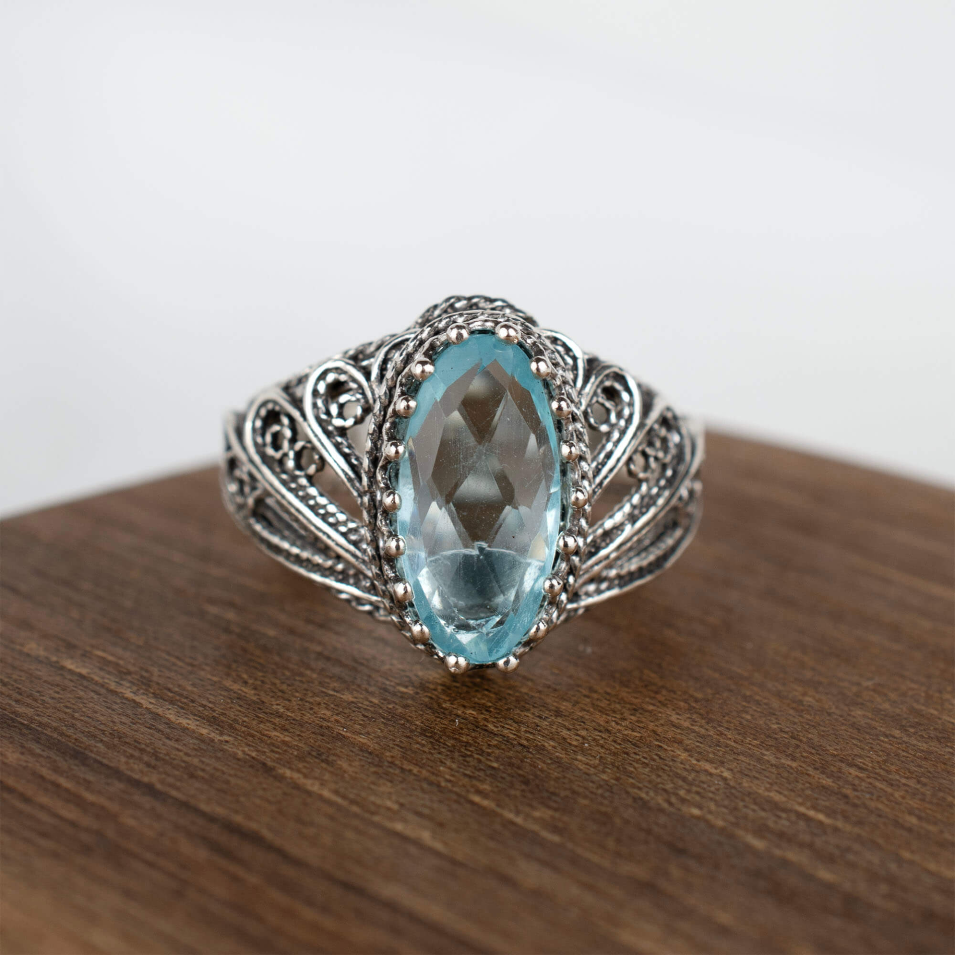 Silver cocktail ring with filigree blue topaz gemstone angel design for women, featuring intricate jewelry craftsmanship.