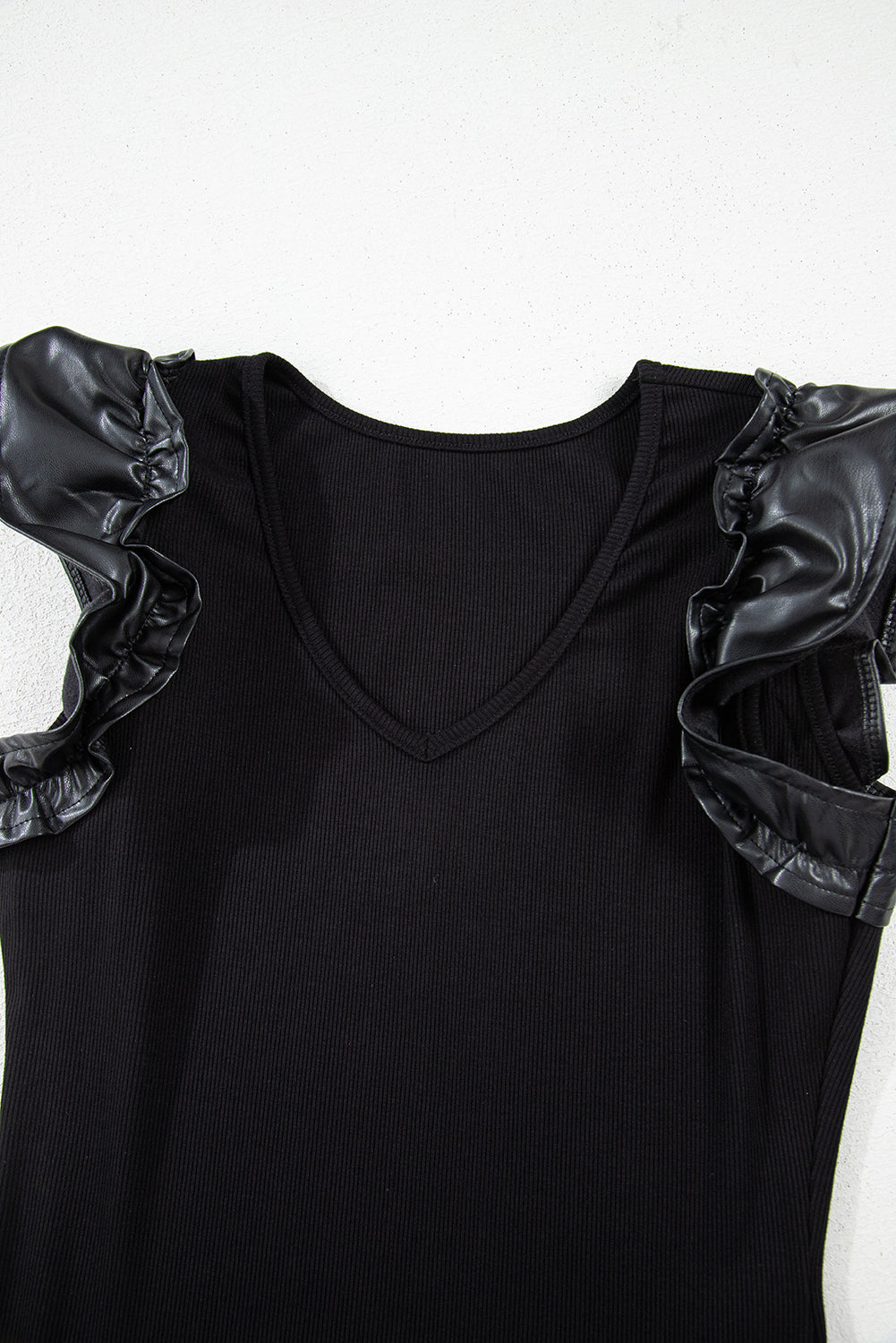 Solid ribbed leatherette ruffle sleeve bodysuit by Byzantium Bay, featuring textured fabric and stylish ruffle accents.