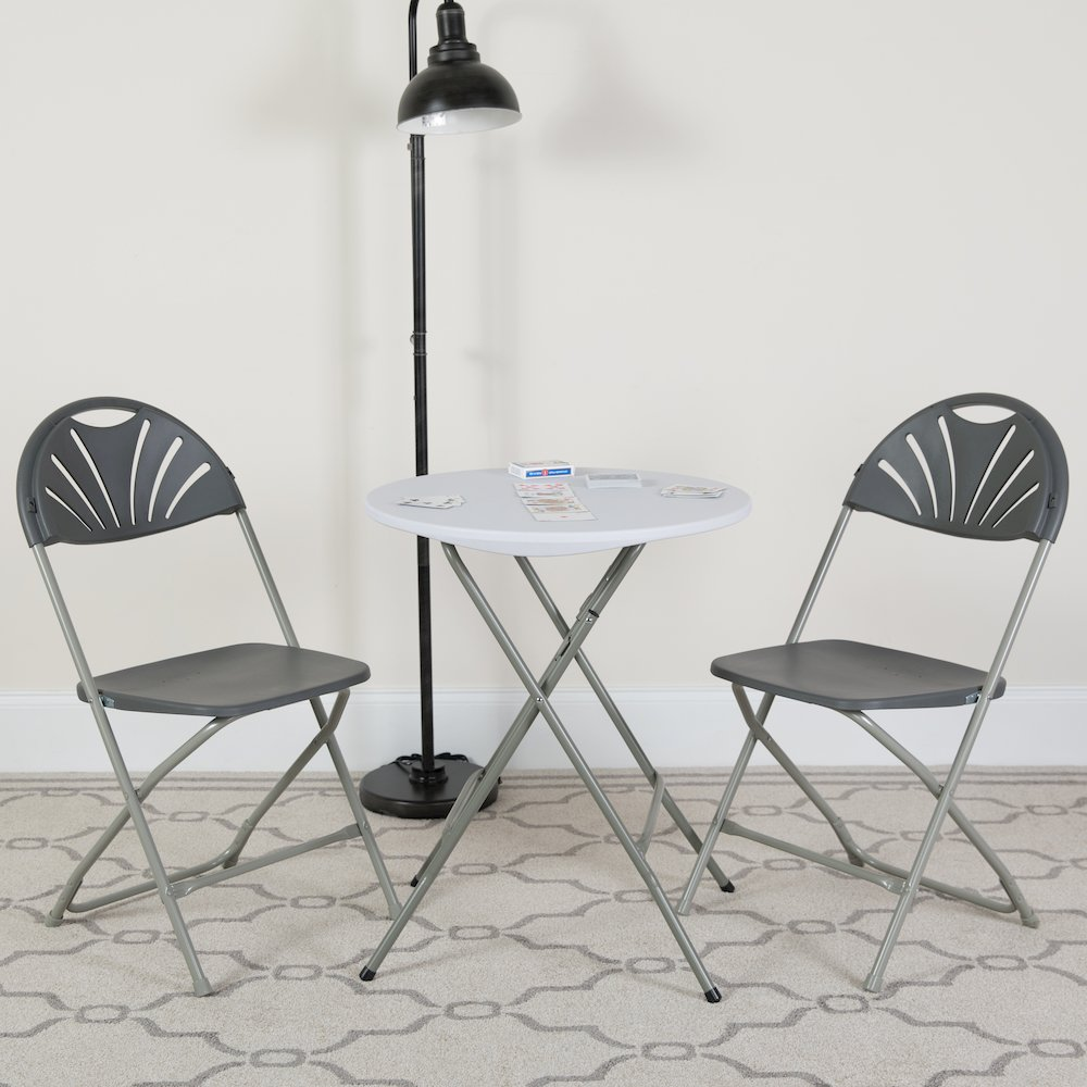 Two HERCULES Series 650 lb. capacity charcoal plastic fan back folding chairs by Start2Finish, shown in a folded and upright position.