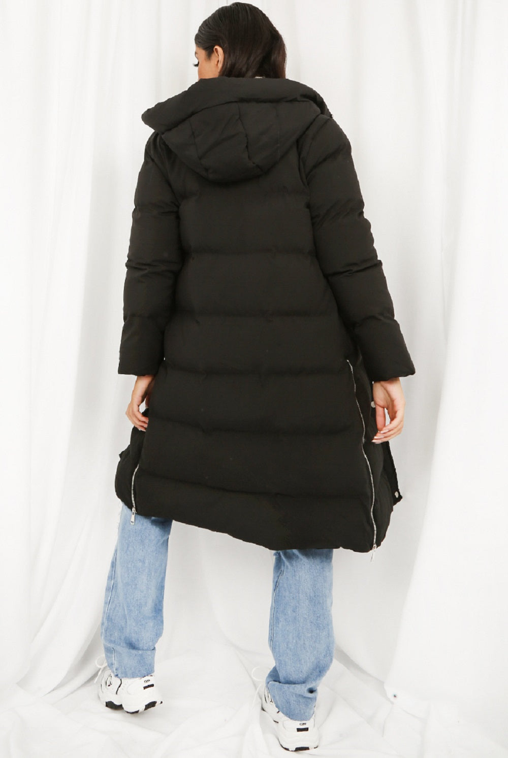 Black hooded longline puffer coat by Rose Eleusis, showcasing its padded design and cozy hood for winter warmth.