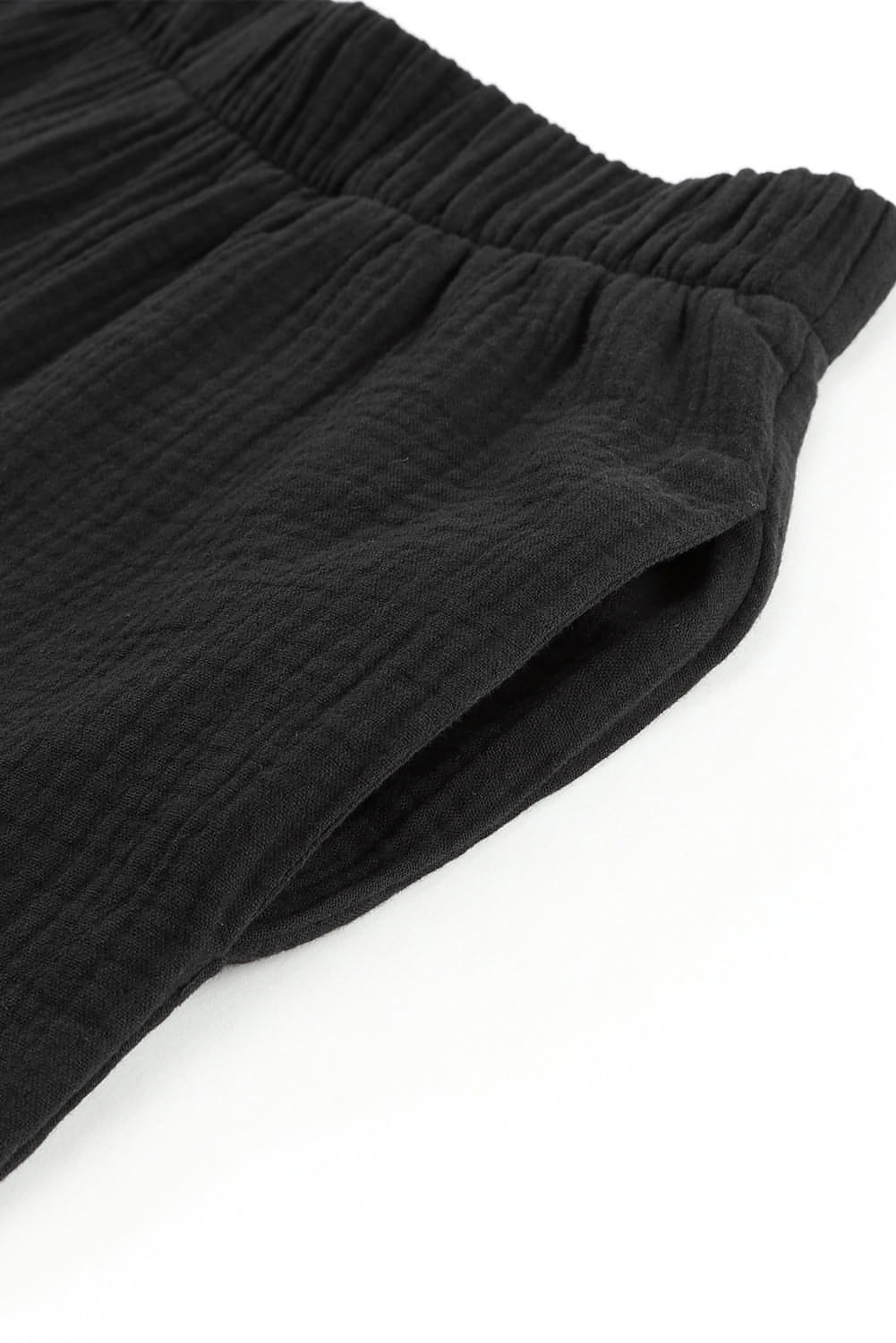 Black textured high waist ruffled bell bottom pants by Carmine Juneberry, showcasing flowy fabric and stylish bell-shaped cuffs.