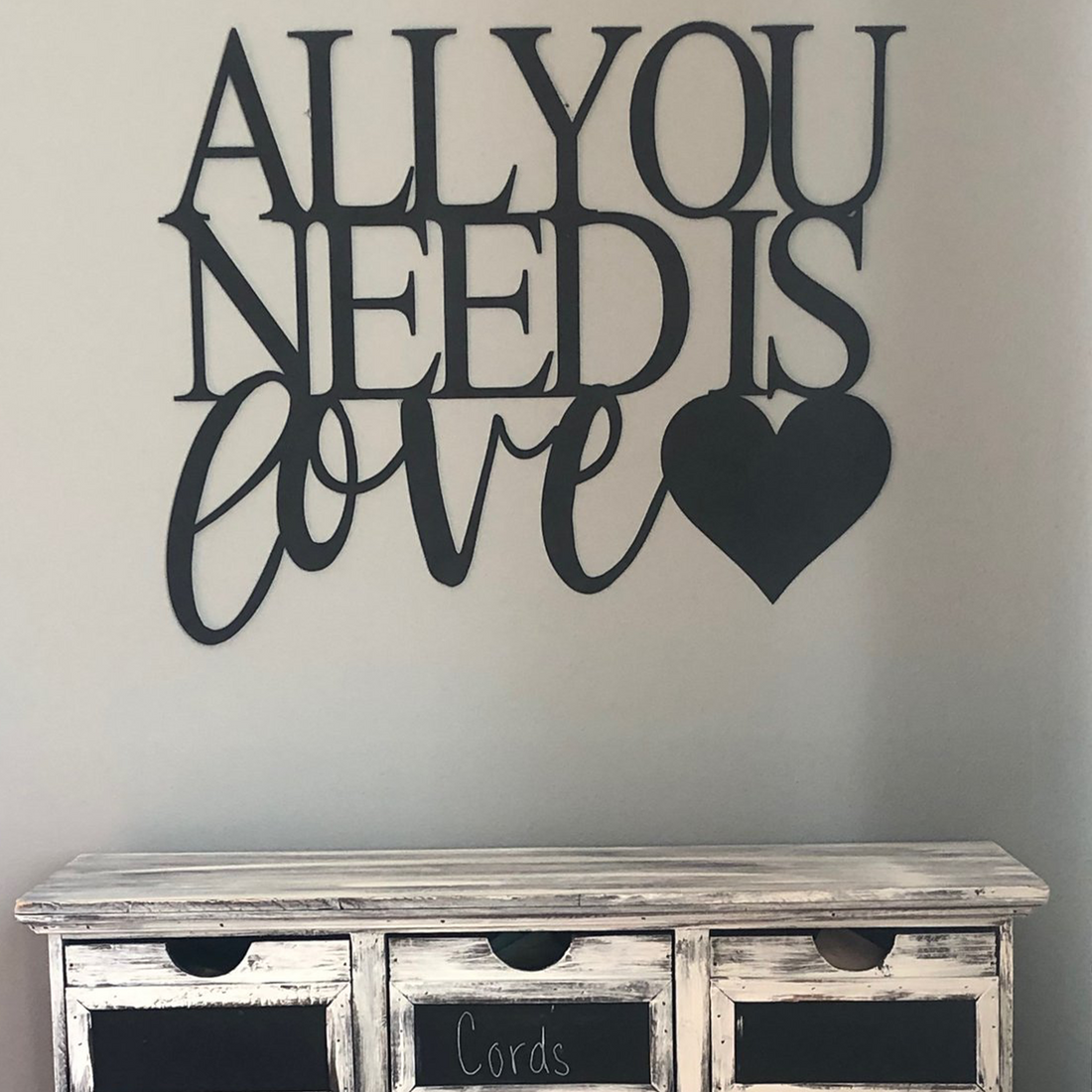 Malachite metal wall art featuring "All You Need Is Love" design hanging above a dresser in home decor style.