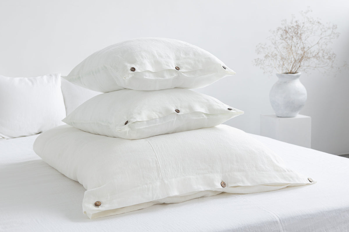 White linen bedding set with coconut button accents, stylish home decor by Magenta Sugarplum, shown on a neatly made bed.