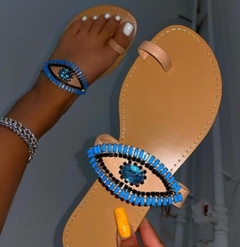 Female rhinestone eyes fashion slides by Coffee Jasper featuring round toe flat slippers with sparkling rhinestone accents.