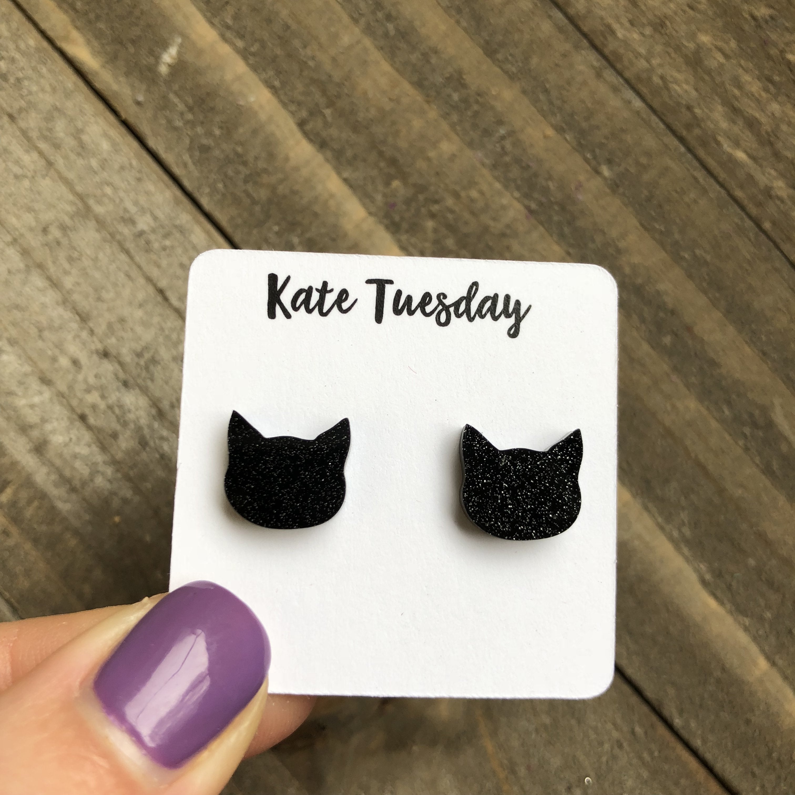 Black glittery acrylic cat earrings by Olive Felix, featuring playful cat-shaped design with shimmering surface.