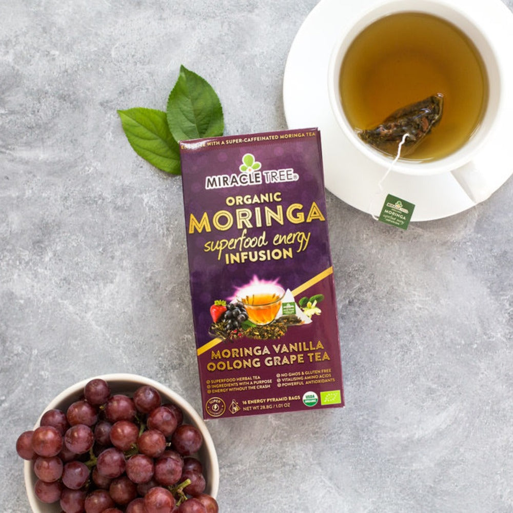 Organic Moringa Energy Tea by Gold Milo in a grape vanilla flavored beverage with tea leaves and ingredients visible in the image.