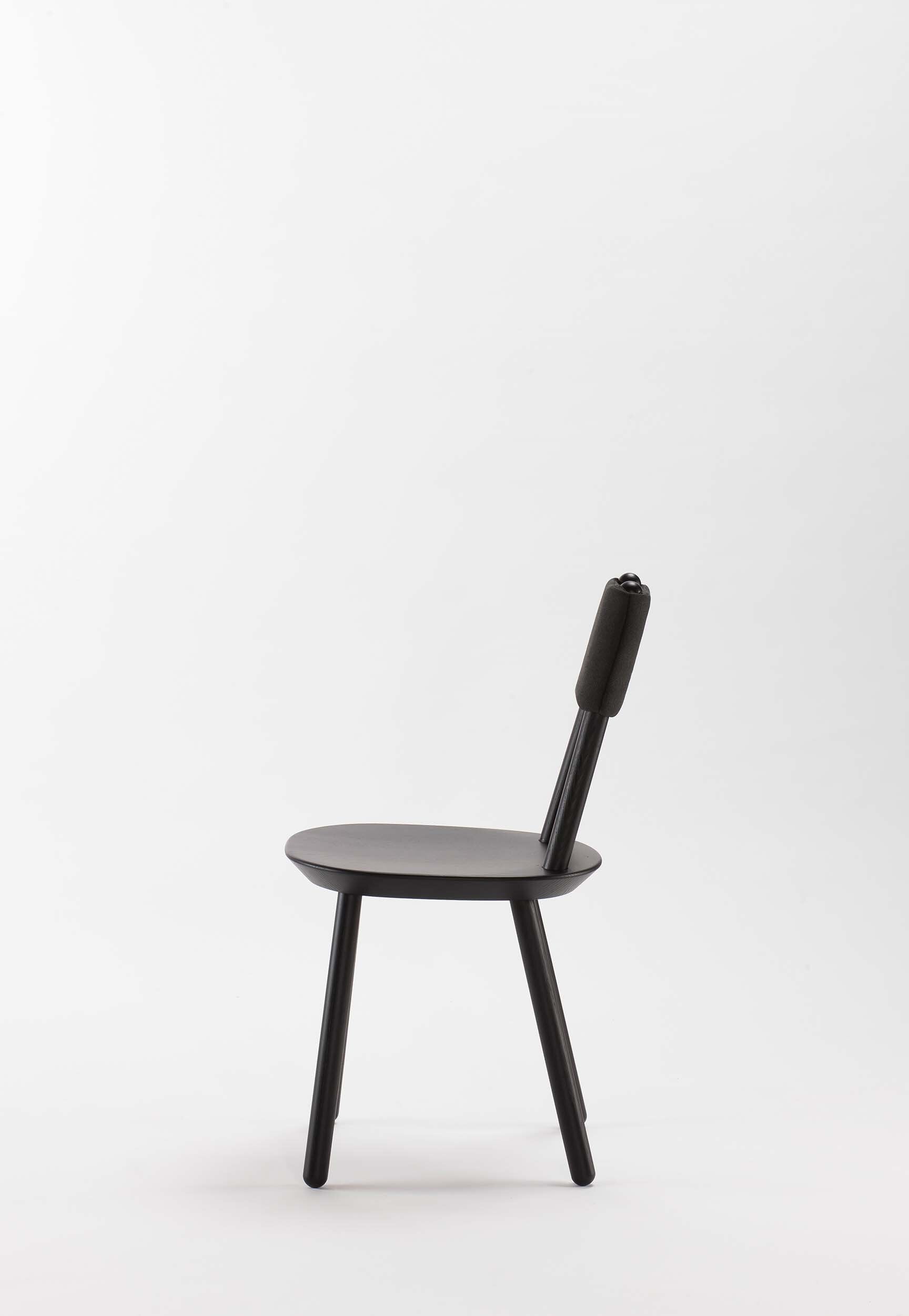 Naïve black dining chair by Aquamarine Poppy featuring a modern, sleek design with a curved backrest and wooden legs.