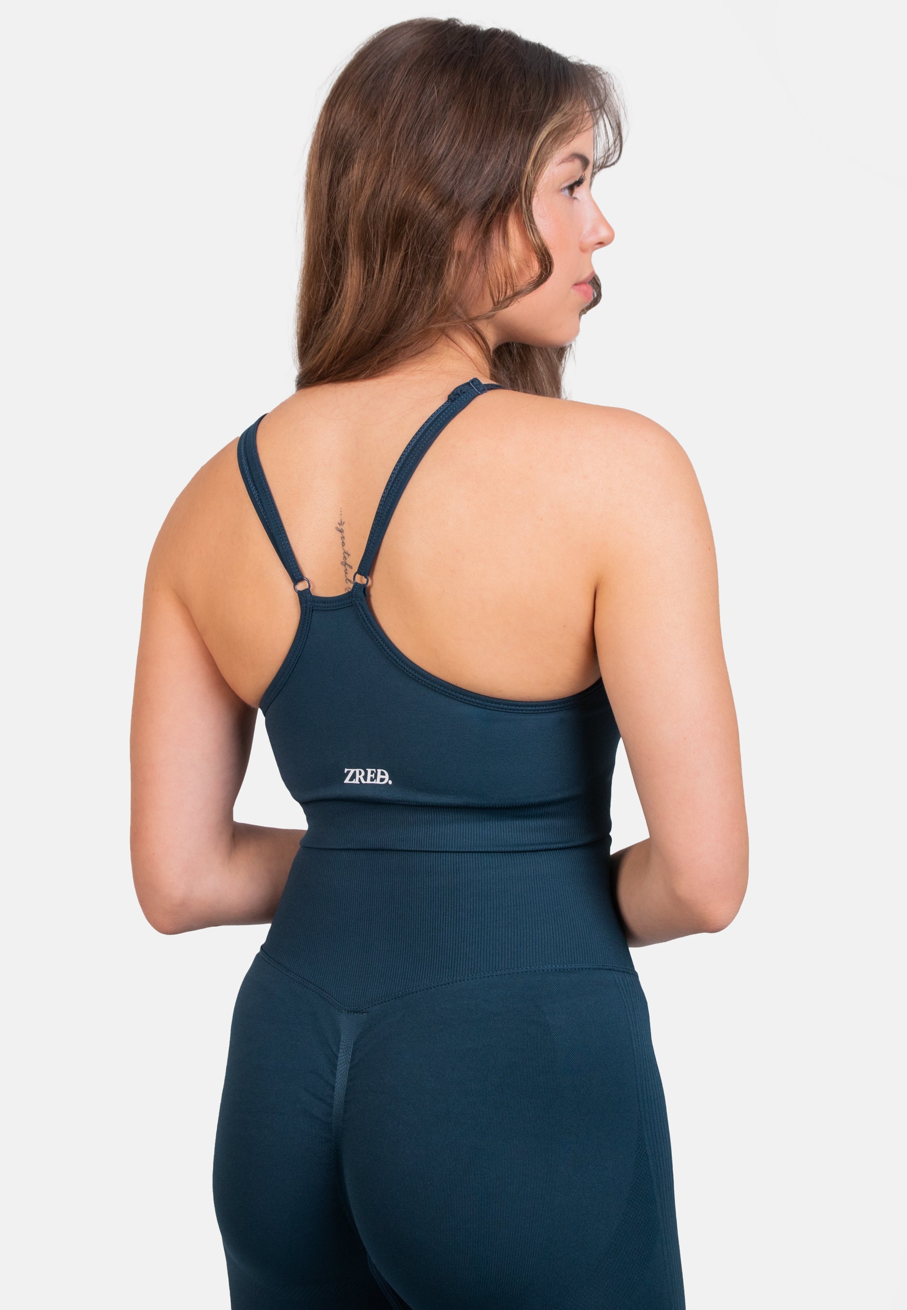 Dark teal Pear Juniper Shape Seamless Sports Bra shown from the back, highlighting its sleek, supportive design for active wear.