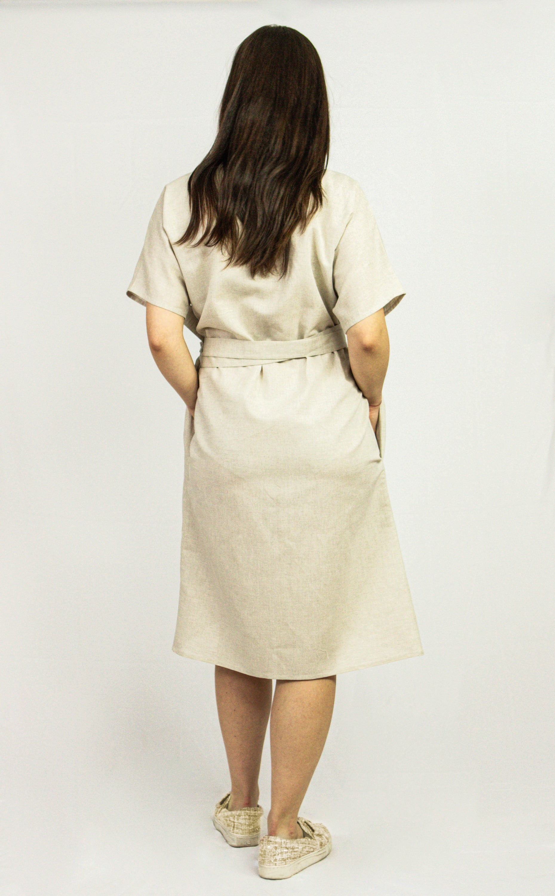 Pale pink linen wrap dress from Magenta Sugarplum featuring a fitted waist and flowing skirt, perfect for warm weather.