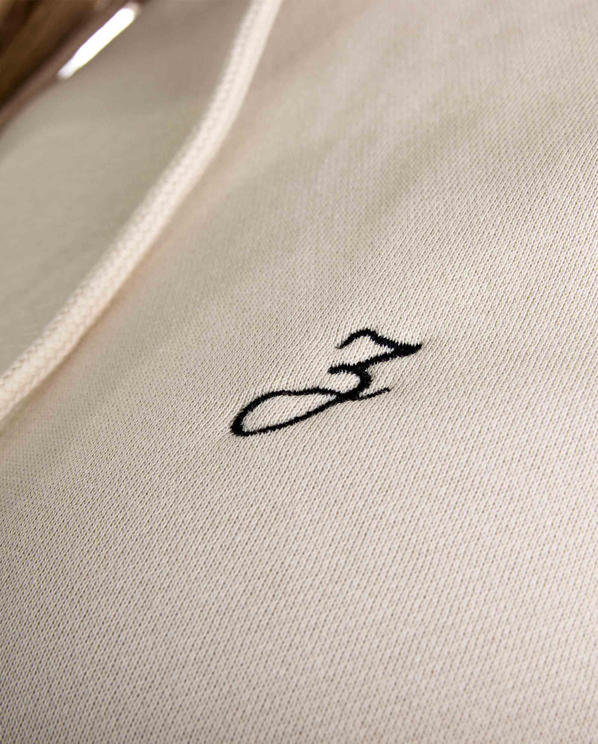 Close-up of Pear Juniper HIGH STD hoodie in sand, showing the fabric texture and hood details on a men&