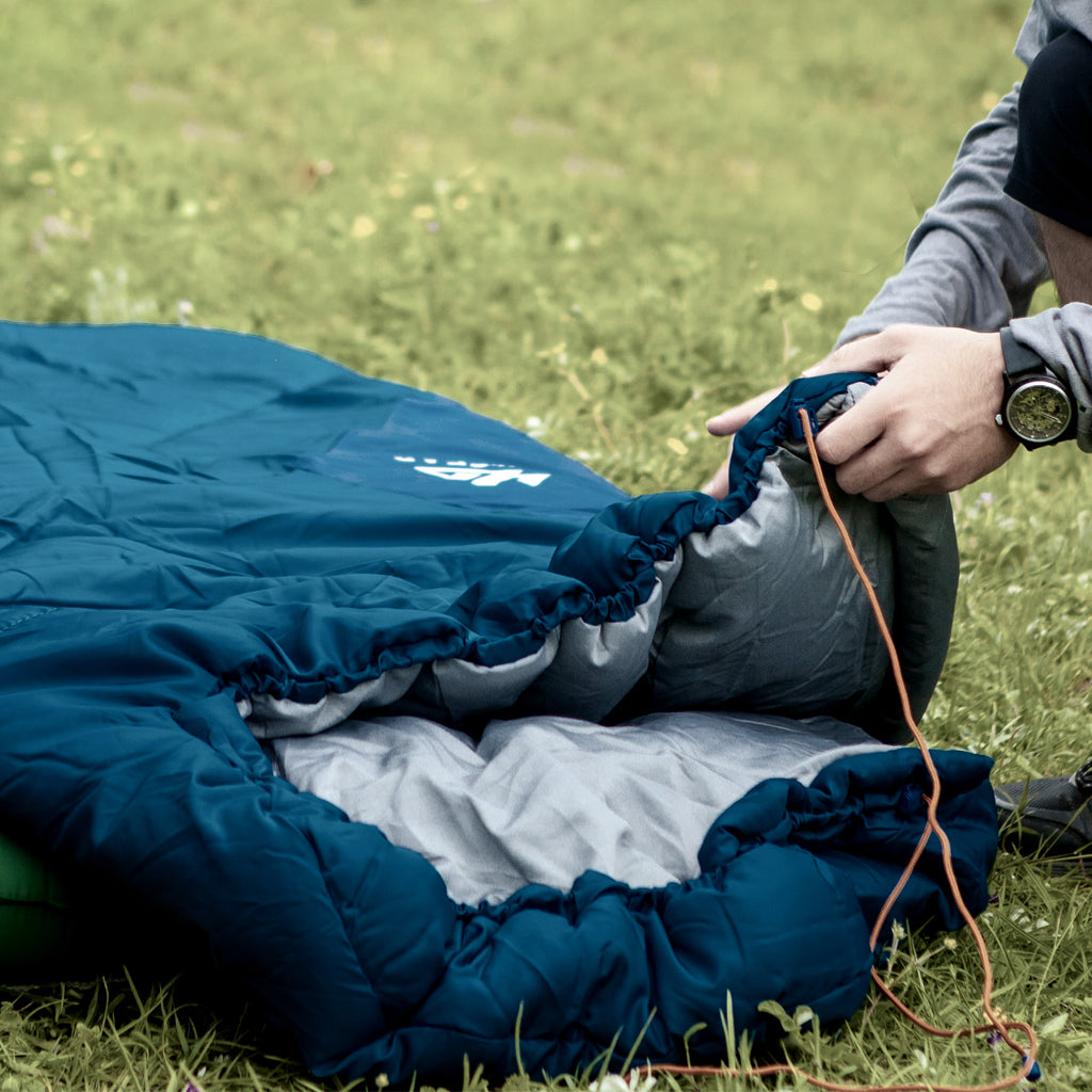 Indigo Eurybia Camfy 30 sleeping bag for camping, shown outdoors with its compact, insulated design and adjustable hood.