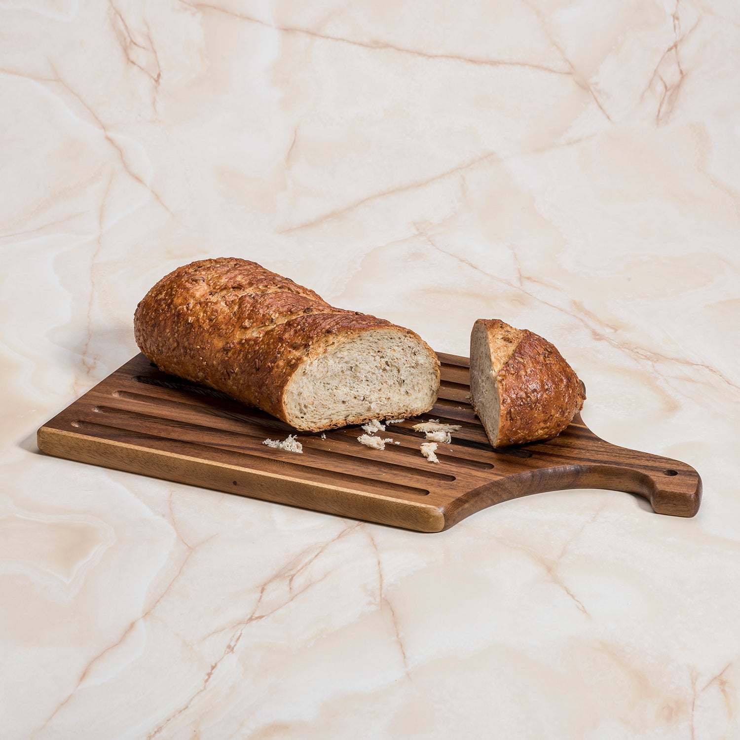 Azure Lily acacia wood slotted bread board, 10x18 inches, ideal for slicing and serving bread in a stylish kitchen setting.