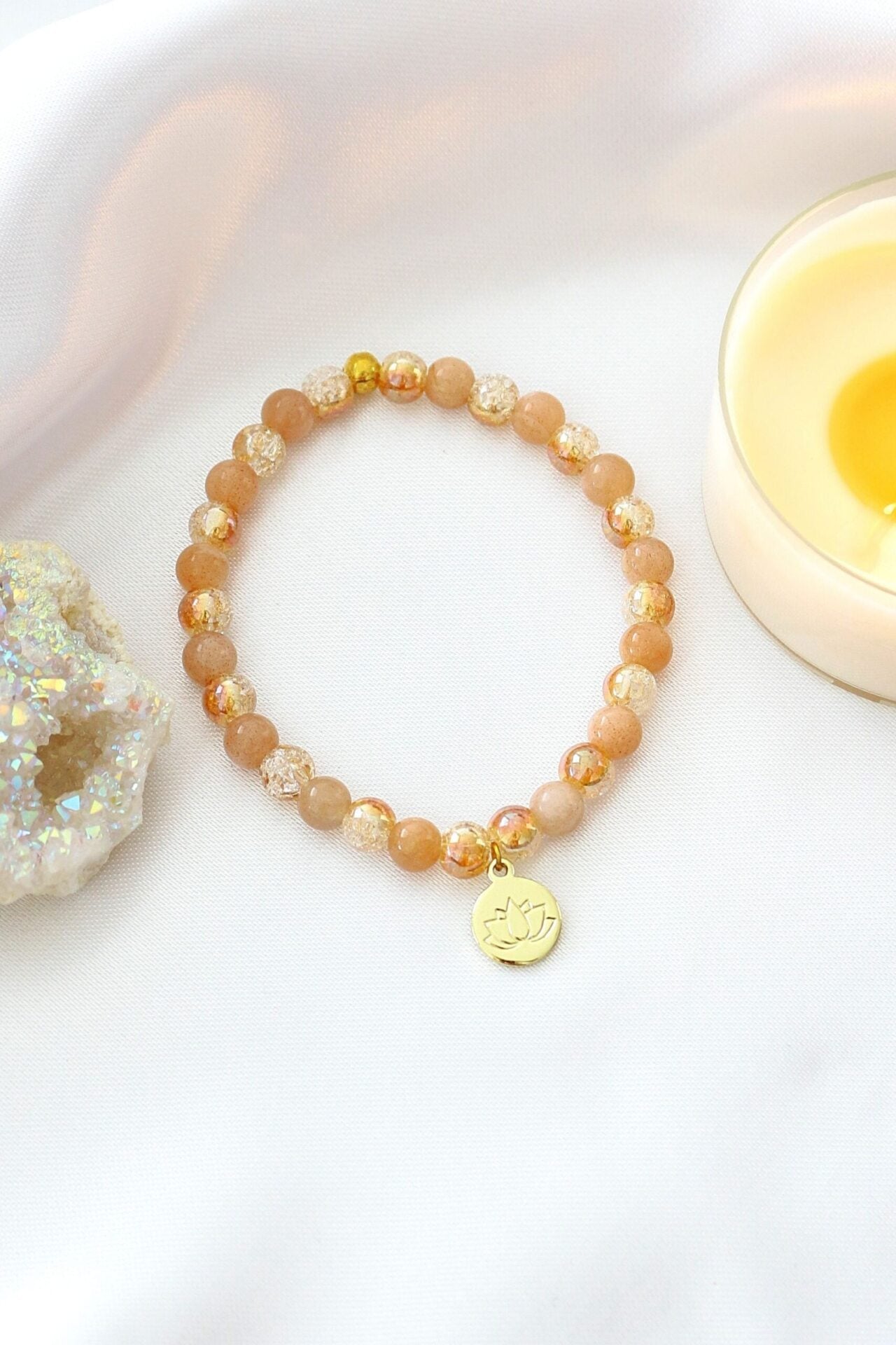 Sunstone elastic bracelet with 24K lotus flower charm by Ultramarine Birch, featuring vibrant orange sunstone beads and a gold lotus pendant.