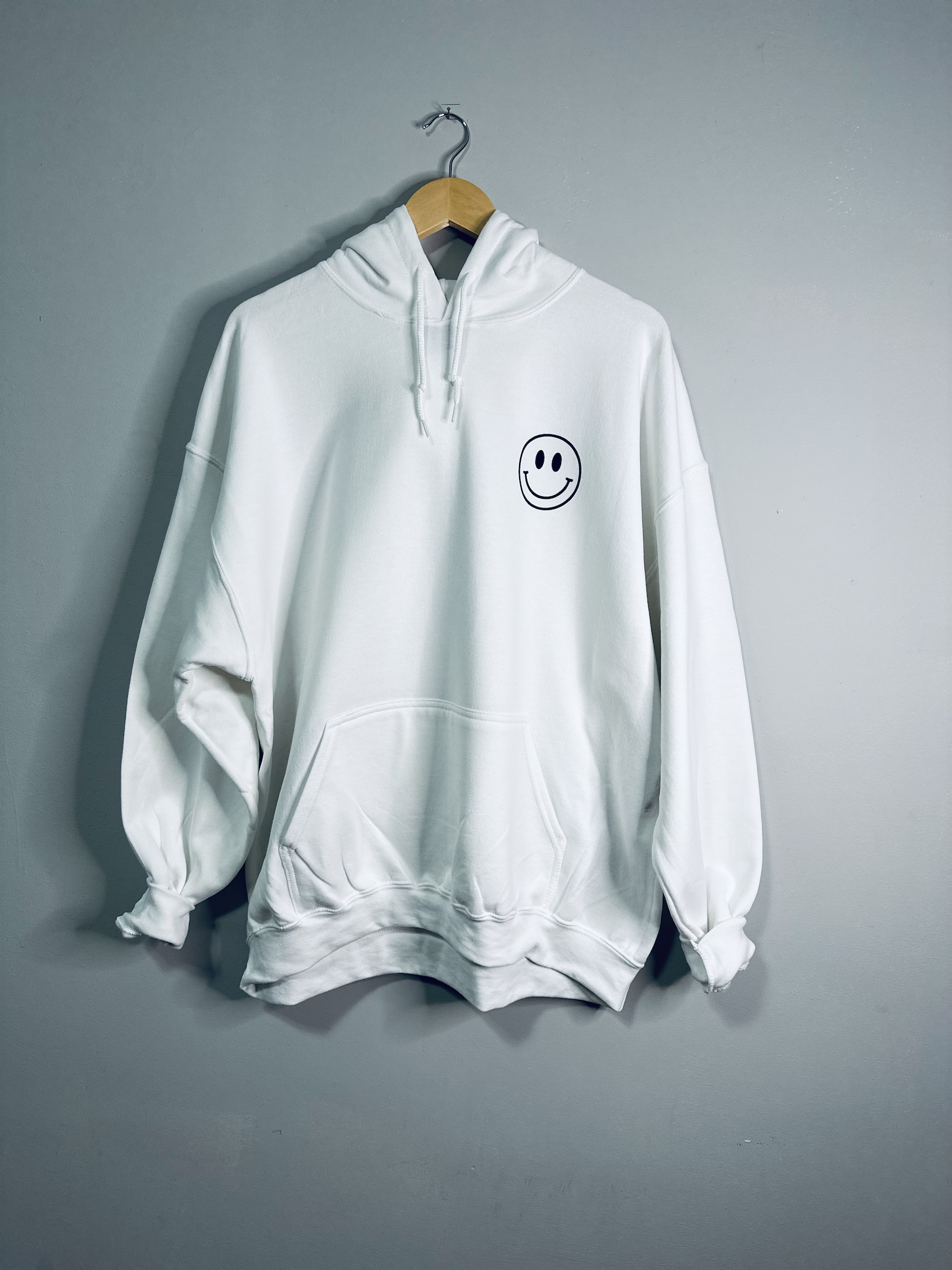 White hoodie from Emerald Ourea with "Dear Person Behind Me" text, casual sweater hoodie with front pocket and drawstrings.