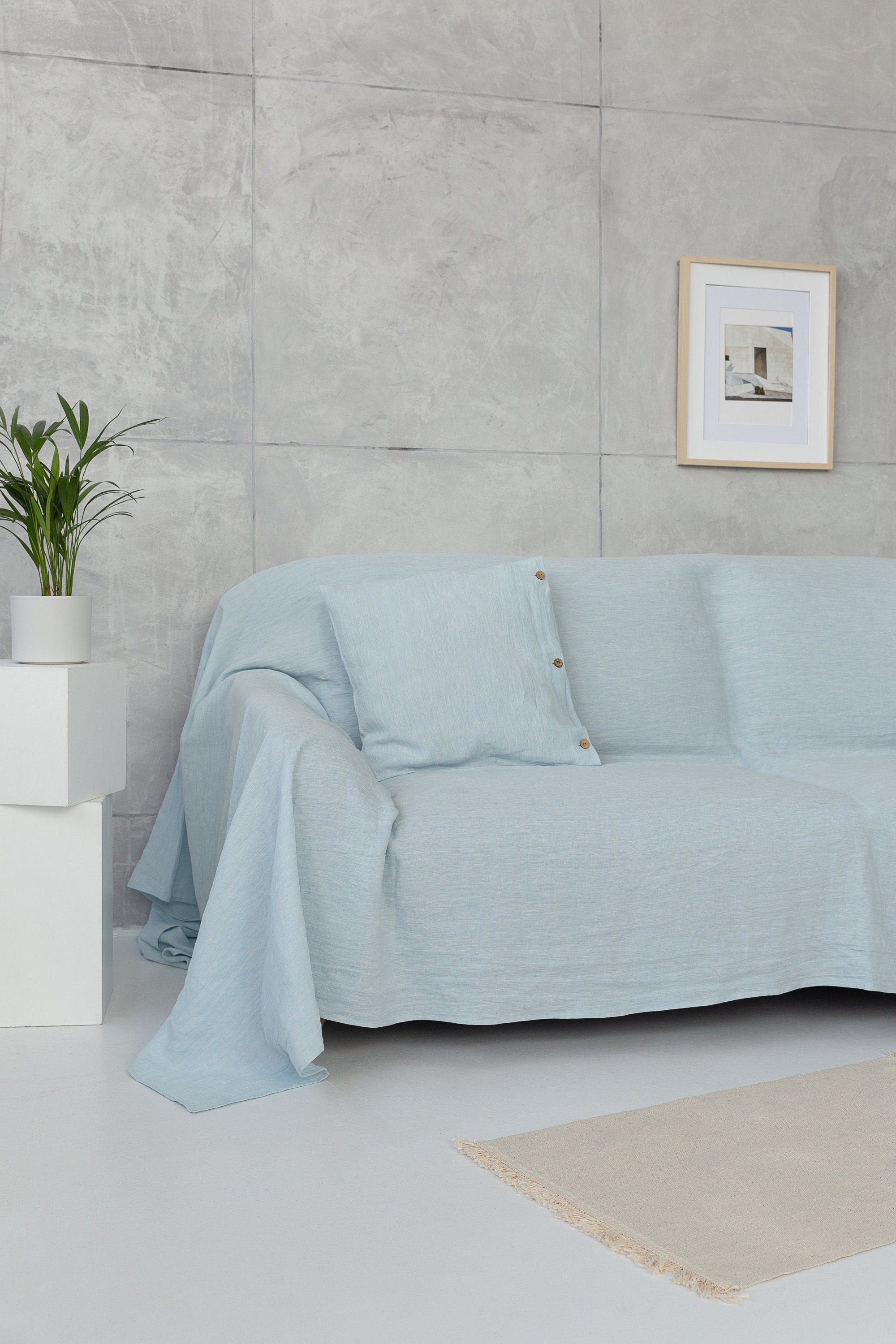 Baby blue linen couch cover by Magenta Sugarplum, draped over a sofa with a cozy, textured appearance in a home decor setting.