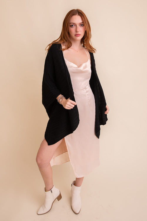 Black ridged rib knit ruana by Periwinkle Aether, open-front layering wrap with textured ribbing and draped silhouette.