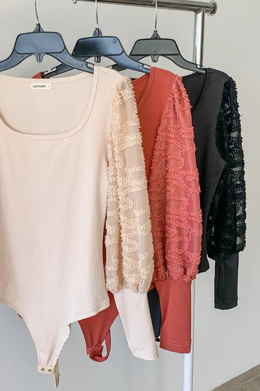 Women’s textured puff sleeve bodysuit by Jade Icarus, showing the detailed fabric and stylish puff sleeves.