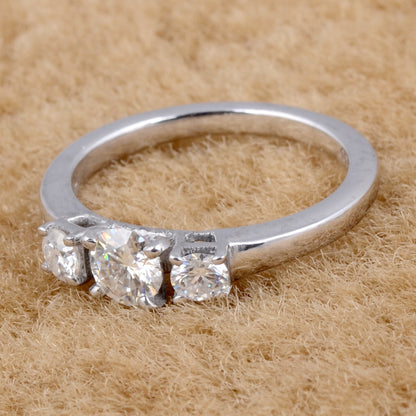 Sterling silver white moissanite 3-stone ring with sparkling gemstones, elegant jewelry piece with intricate band detailing.