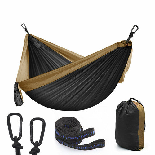 Maroon Asteria camping parachute hammock for outdoor survival, shown hanging in a garden with trees and greenery.