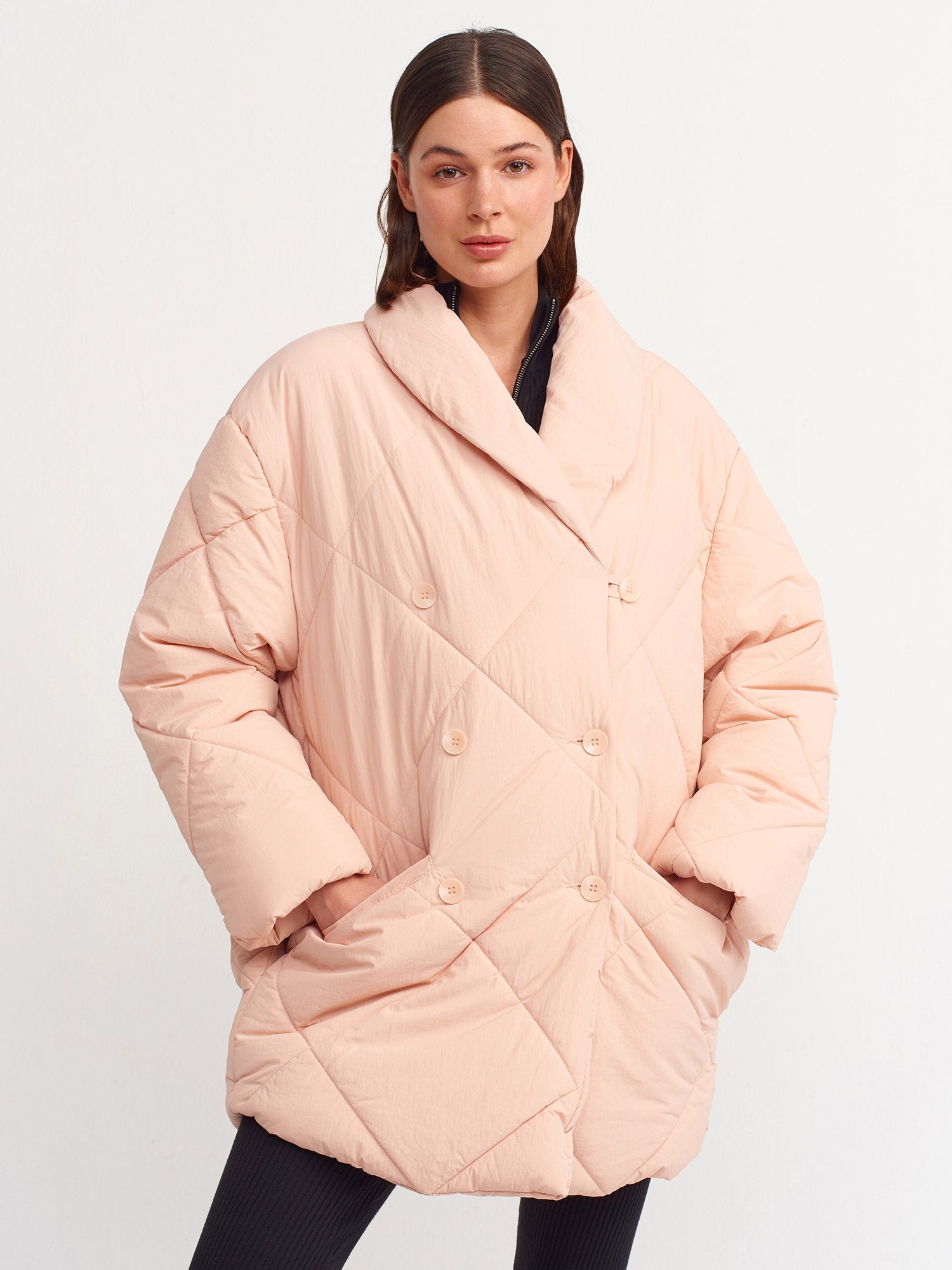 Pink quilted coat for women by Ruby Dionysus, showing a close-up of the padded, stylish outerwear with a high collar.