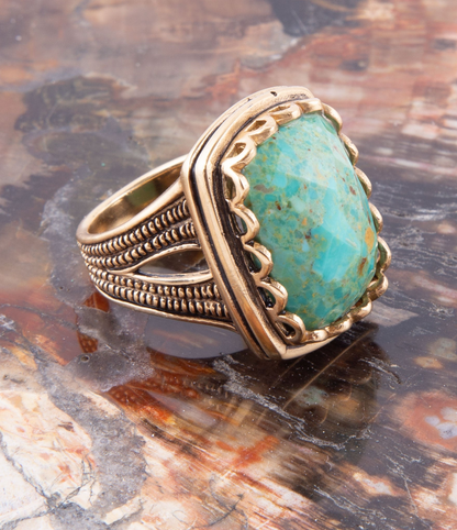 Blue turquoise and gold cocktail ring with intricate jewelry design, featuring a large central turquoise stone and golden accents.