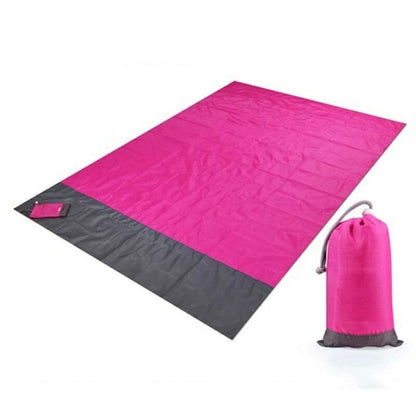 Maroon Asteria portable waterproof picnic and beach mat, camping pocket blanket spread on grass outdoors.