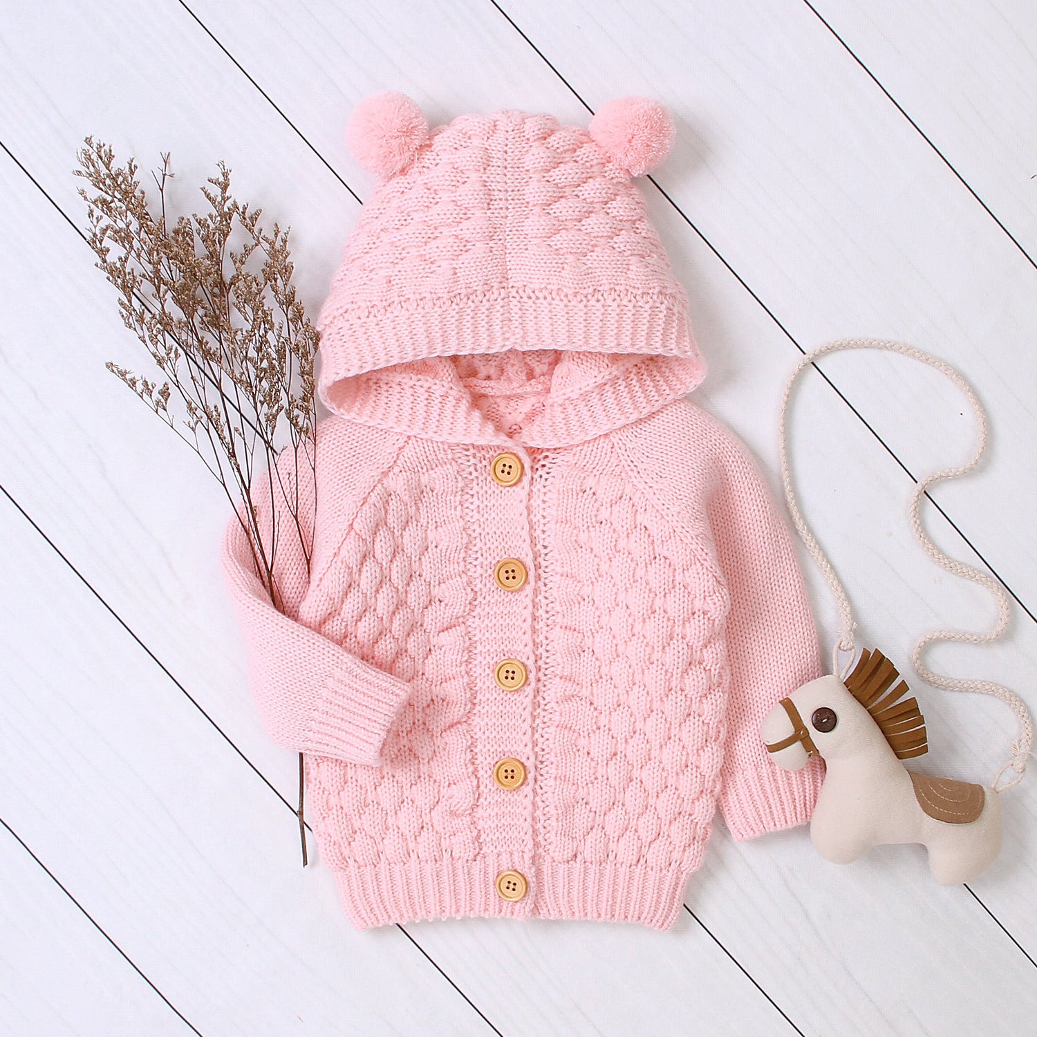 Baby wearing Carmine Juneberry KuschelGlöckchen™ hooded knit jacket with pom-pom, cozy and stylish baby clothing.