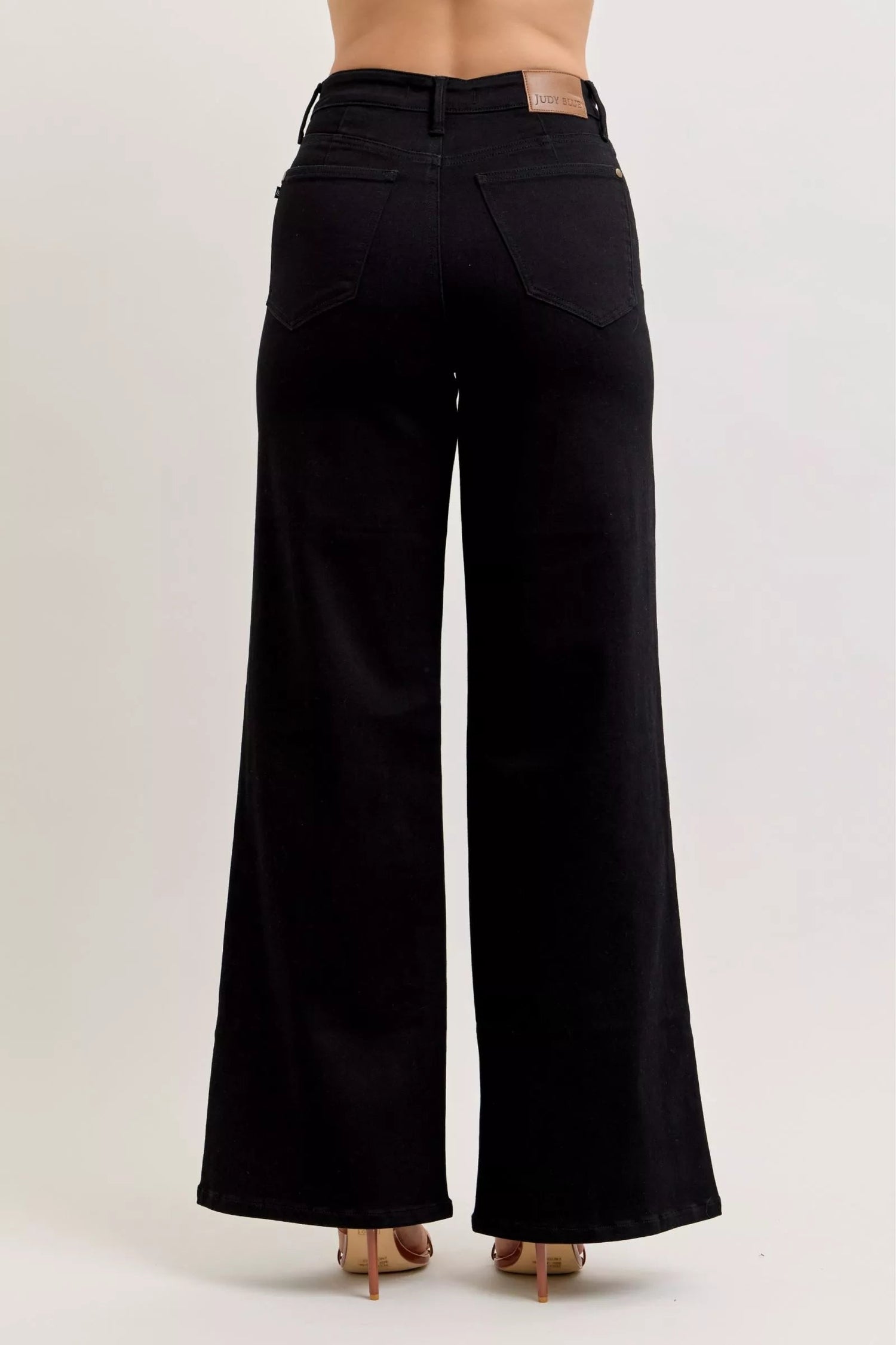 Pear Daisy Judy Blue high-waisted wide leg jeans displayed on a hanger, showcasing denim fabric and fashionable fit.