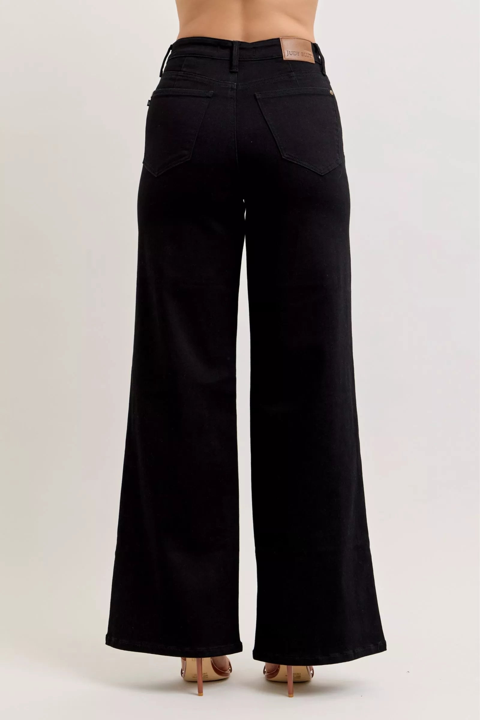 Pear Daisy Judy Blue high-waisted wide leg jeans displayed on a hanger, showcasing denim fabric and fashionable fit.