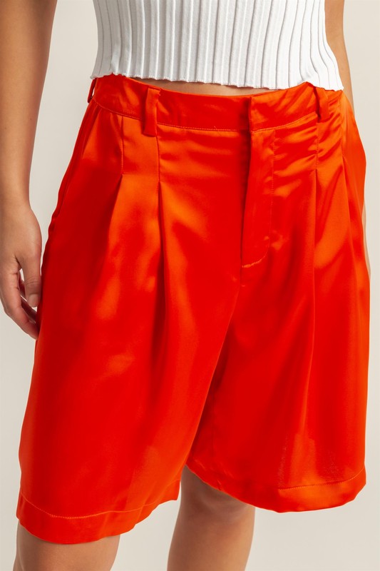 Satin high-waist pleated shorts by Jade Icarus, styled with automotive-inspired details, displayed on a neutral background.