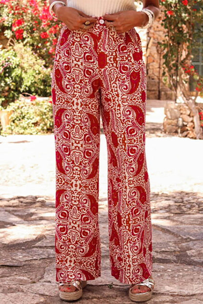 Red paisley printed high waist straight-leg pants by Carmine Juneberry, featuring button detail and tailored fit.