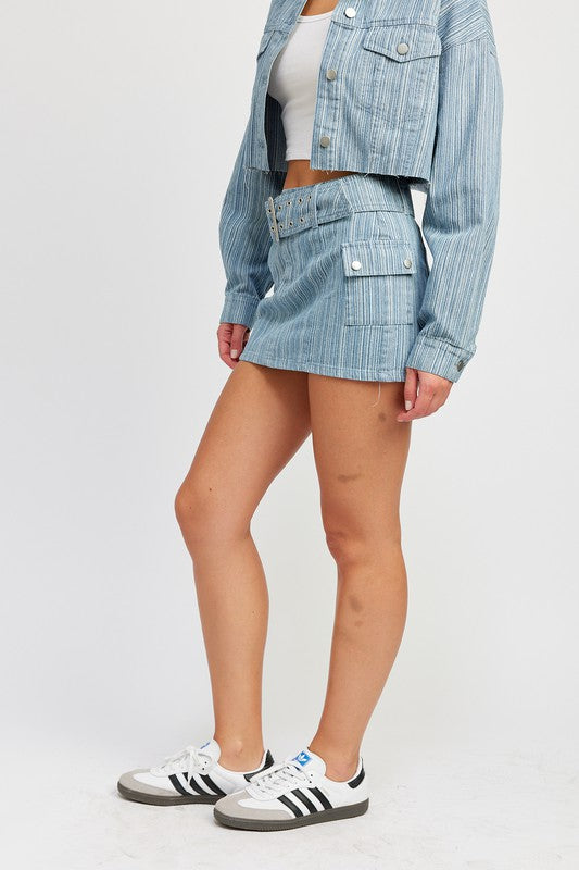 Jade Icarus belted mini denim skirt with automotive-inspired design, shown on a model. Bright blue denim with a stylish belt detail.
