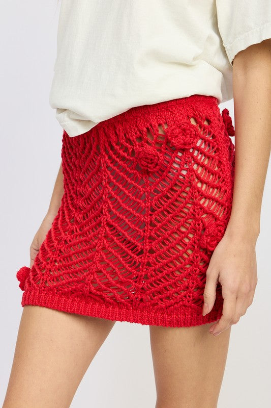 Crochet mini skirt by Jade Icarus featuring rosette details, showcasing intricate knit texture and feminine style.