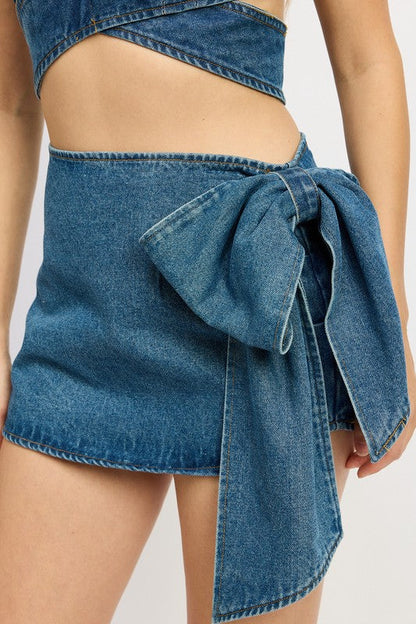 Women’s denim mini skirt with bow detail by Jade Icarus, showcasing the stylish front view and classic denim texture.