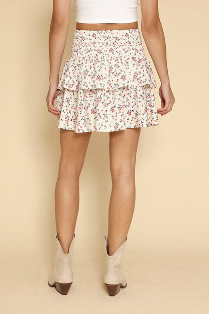 Floral smocked ruffle mini skirt by Jade Icarus, featuring a colorful floral pattern and ruffled hem in a close-up view.