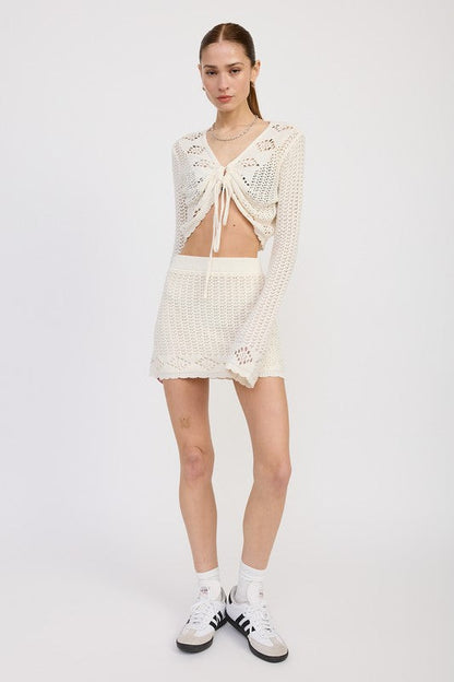 Jade Icarus lettuce hem mini crochet skirt displayed on a model, featuring textured crochet fabric and a stylish, modern design.