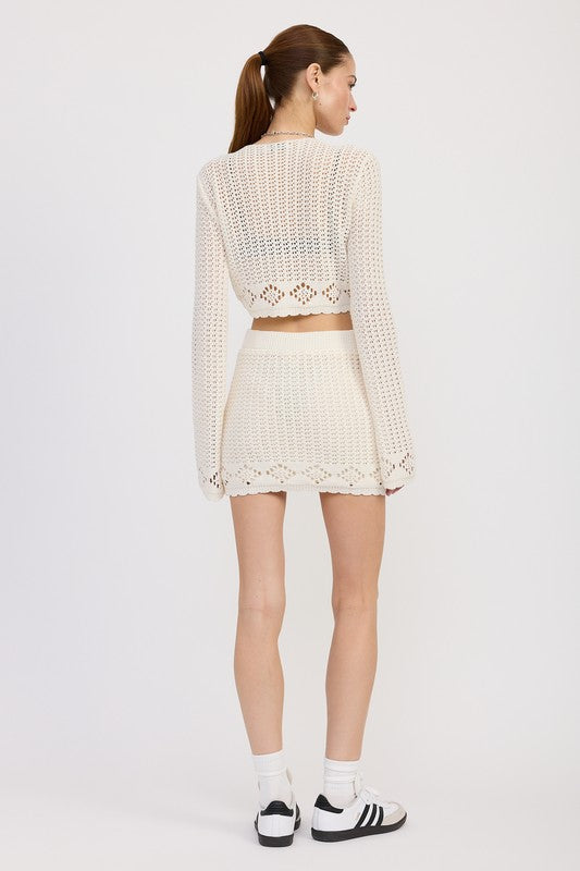 Jade Icarus lettuce hem mini crochet skirt displayed on a model, showing its detailed crochet pattern and stylish fit.