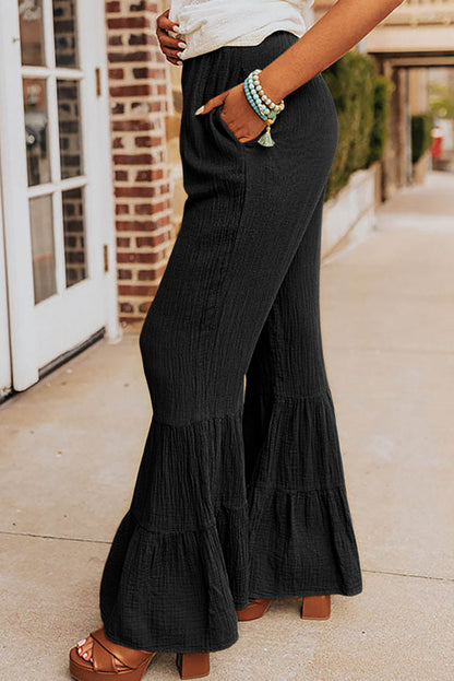 Black textured high waist ruffled bell bottom pants by Carmine Juneberry, showcasing the stylish flared design and ruffle details.