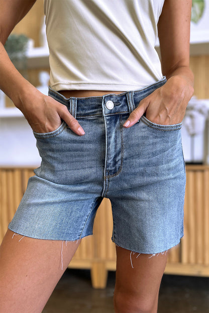 Judy Blue high waist raw hem denim shorts with distressed details, styled for a casual look.