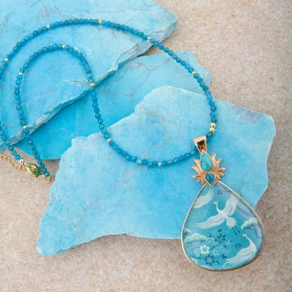 Heron Flight Blue Teal Apatite pendant necklace with gold chain, showcasing a vibrant blue and teal gemstone design.