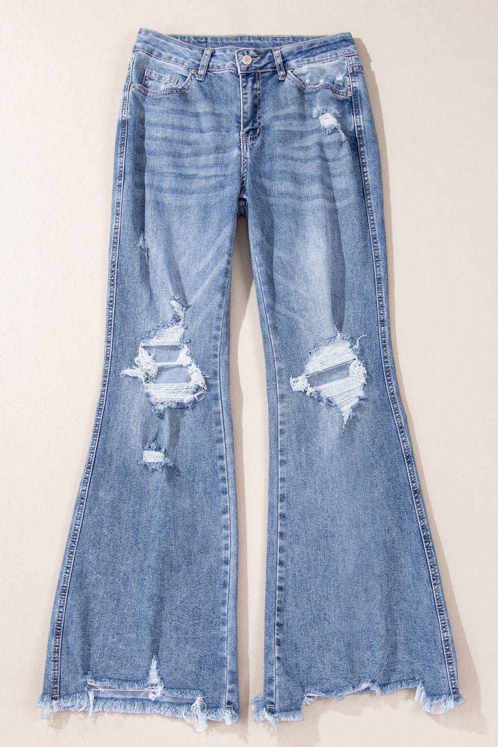 Dusk blue high rise ripped distressed hem flared jeans by Carmine Juneberry displayed on a model.
