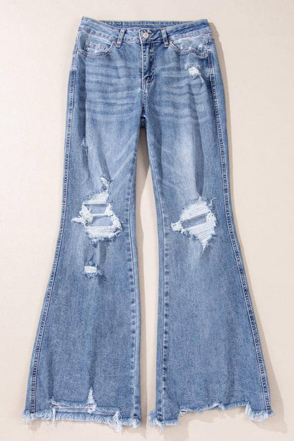 Dusk blue high rise ripped distressed hem flared jeans by Carmine Juneberry displayed on a model.