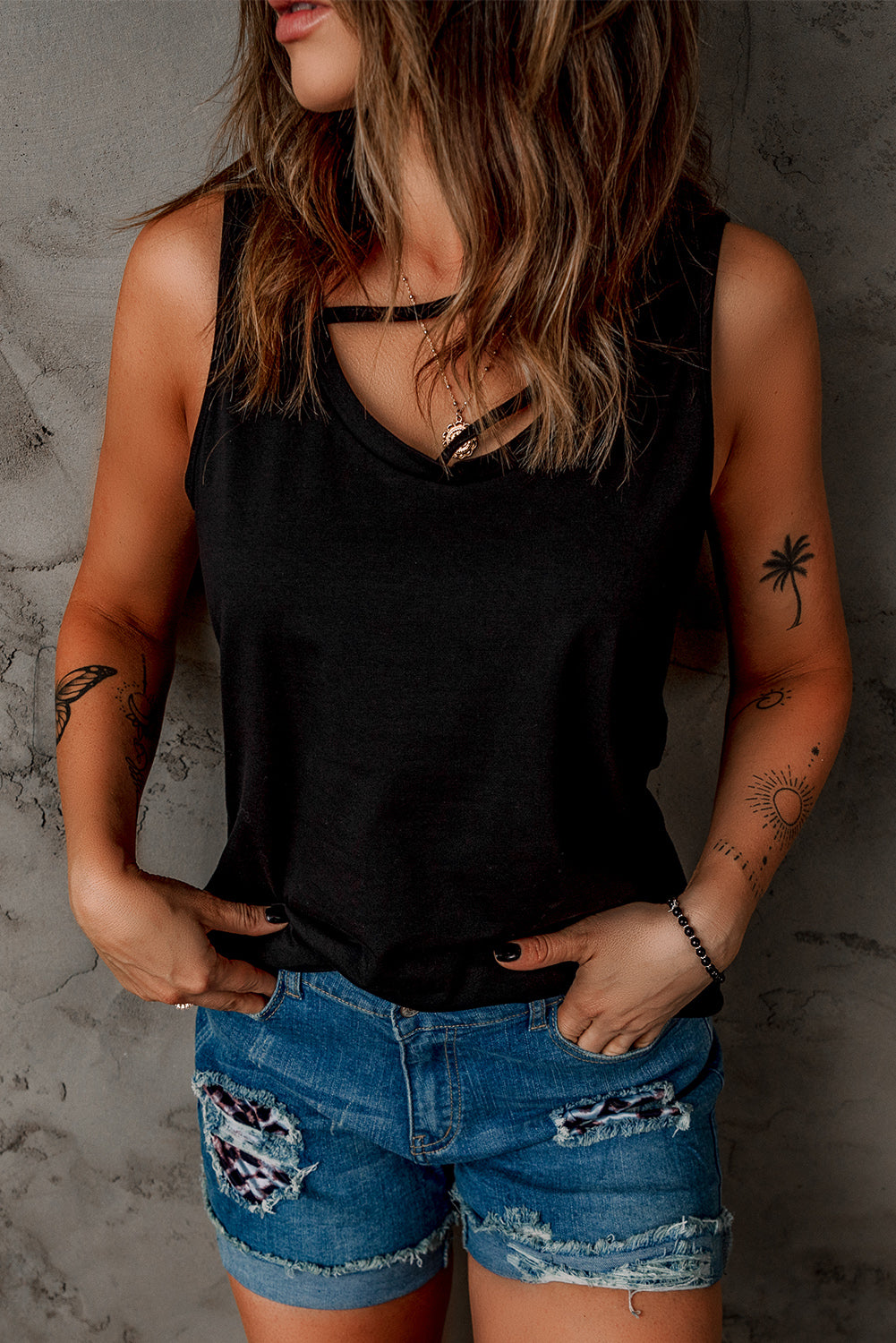 Black strappy hollow-out neck tank top by Harlequin Daisy, featuring a stylish design and lightweight fabric.