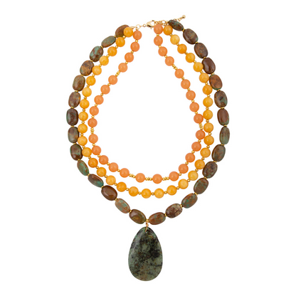 Green Chrysocolla pendant on a gold necklace, jewelry featuring a polished stone with vibrant green and blue tones.
