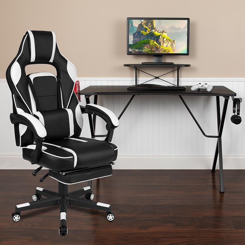 Black gaming desk with headphone hook, monitor stand, and white gaming chair with armrests, featuring a modern furniture design.