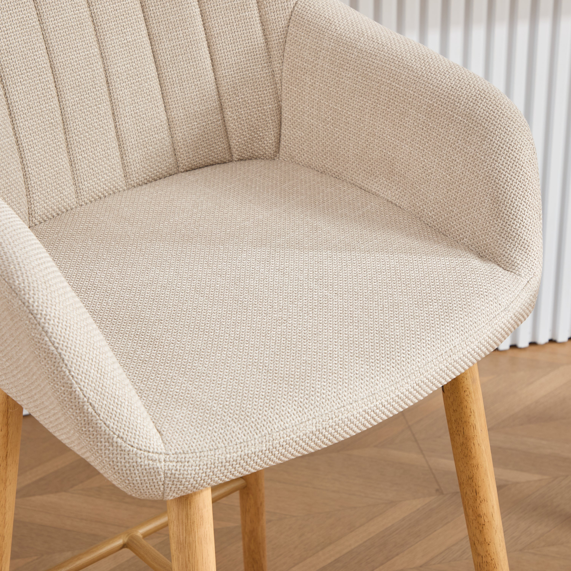 Modern linen upholstered bar stool with back, armrests, footrest, and solid wood legs, designed for stylish kitchen or bar seating.