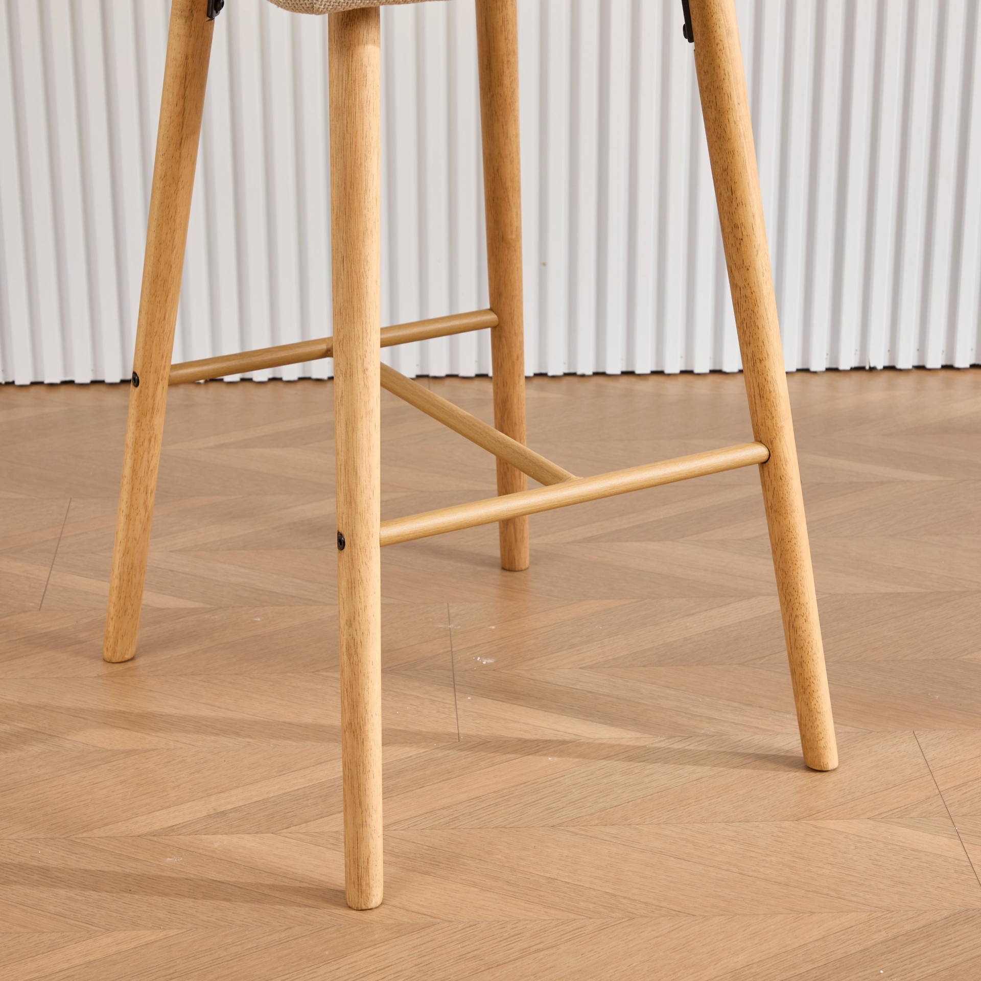 Modern linen upholstered bar stool with back, armrests, footrest, and solid wood legs, featuring stylish furniture design.